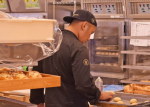 厨房釜担当のユニフォーム。帽子とコックコートにゴールドのロゴ刺繍